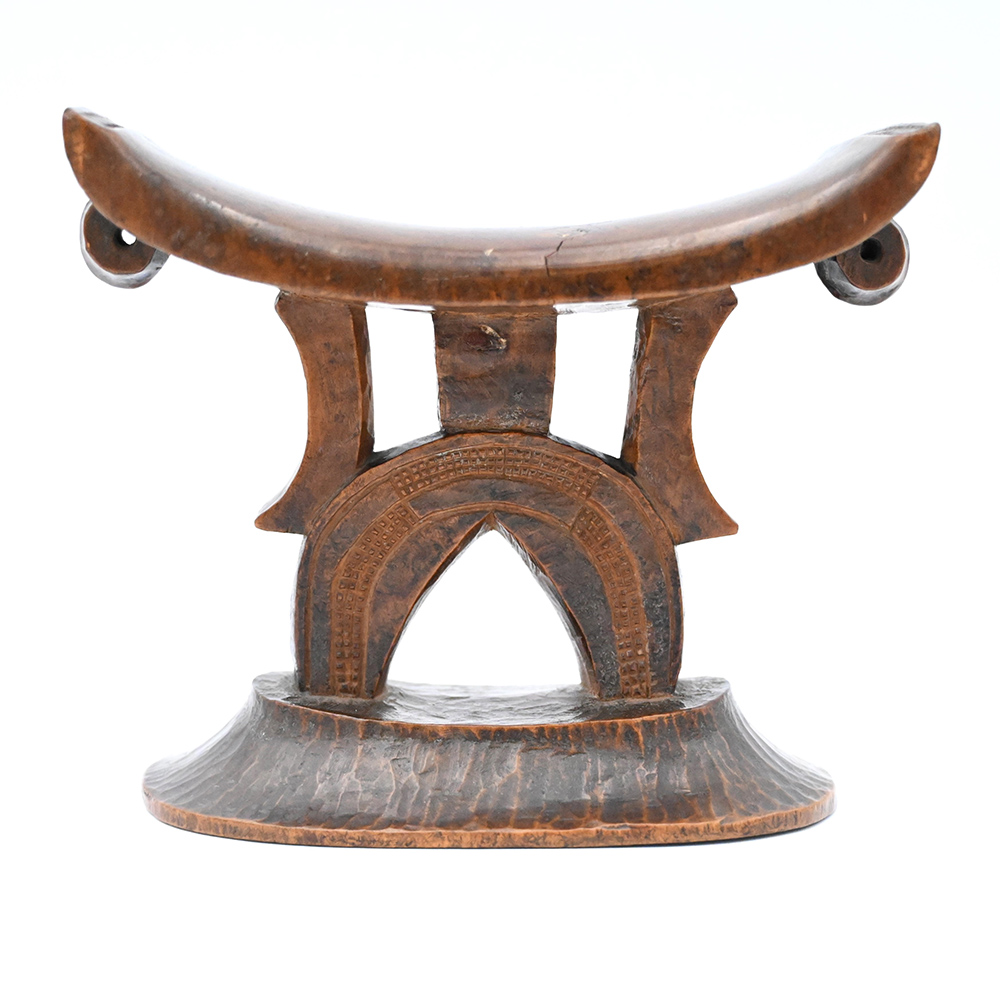Wooden headrest with features in the base resembling a torso and legs