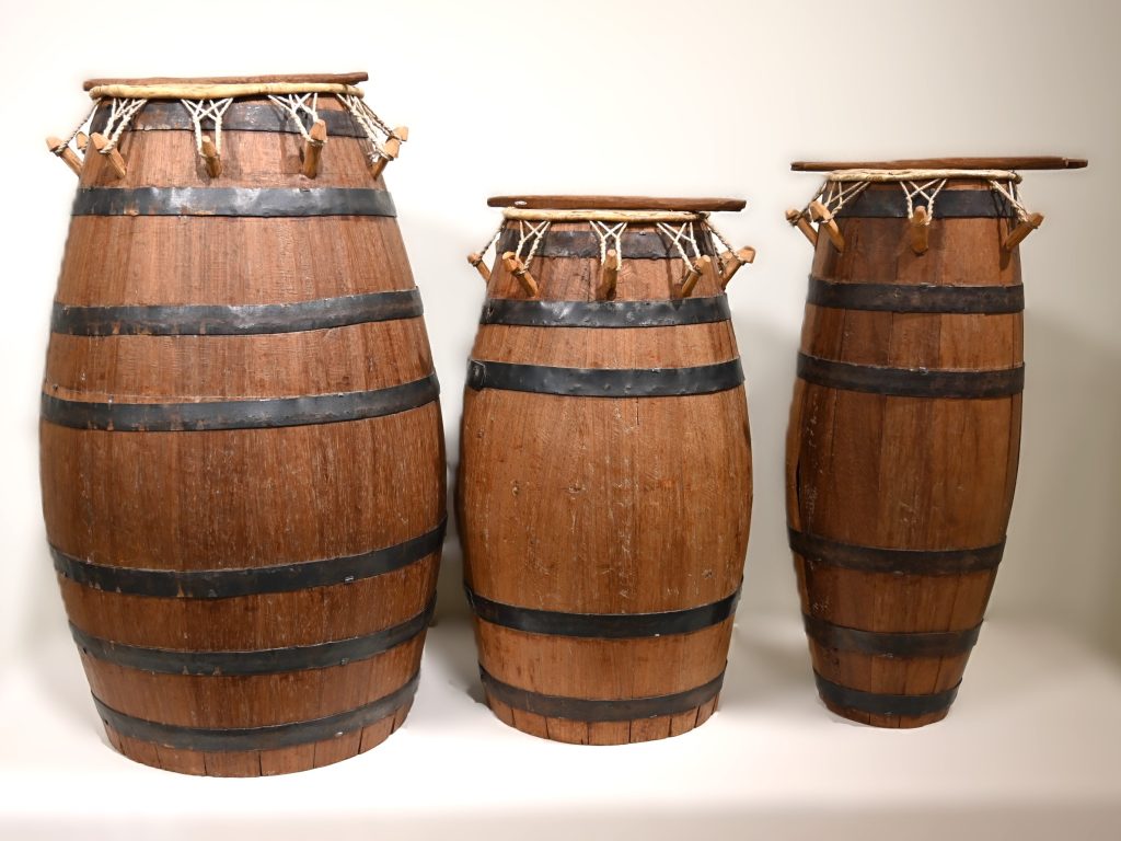 3 wooden drums with metal bands around the bodies and drumsticks
