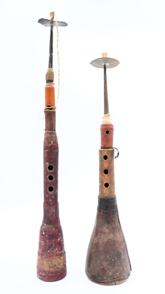 Two oboes with wood bodies and metal disc shaped mouthpieces holding reeds