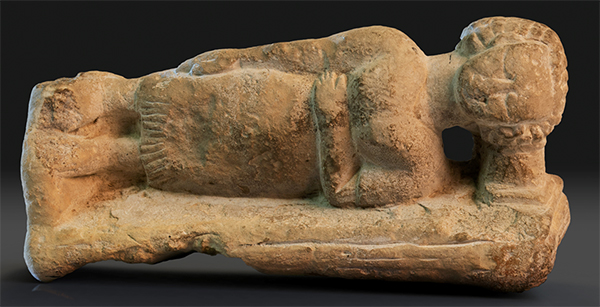 Limestone carving of an Egyptian woman sleeping with a headrest.