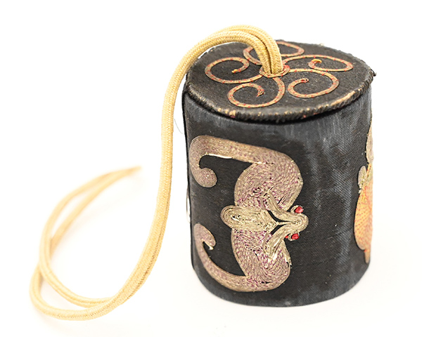 Small cylindrical silk box with a string loop at the top